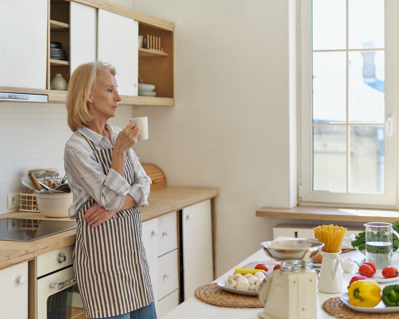 A woman in her kitchen with her morning coffee